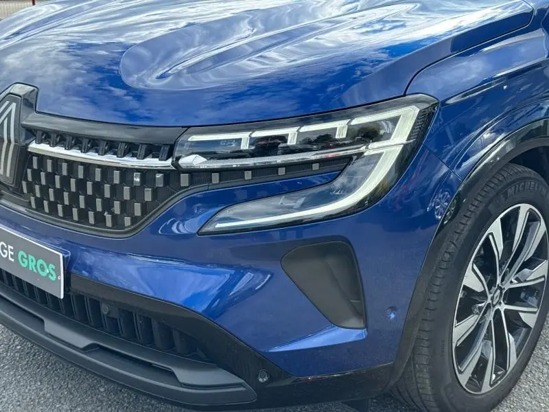 Gros plan sur l'avant droit du Renault Austral 2025 bleu Outremer avec calandre noire et phares LED distinctifs.