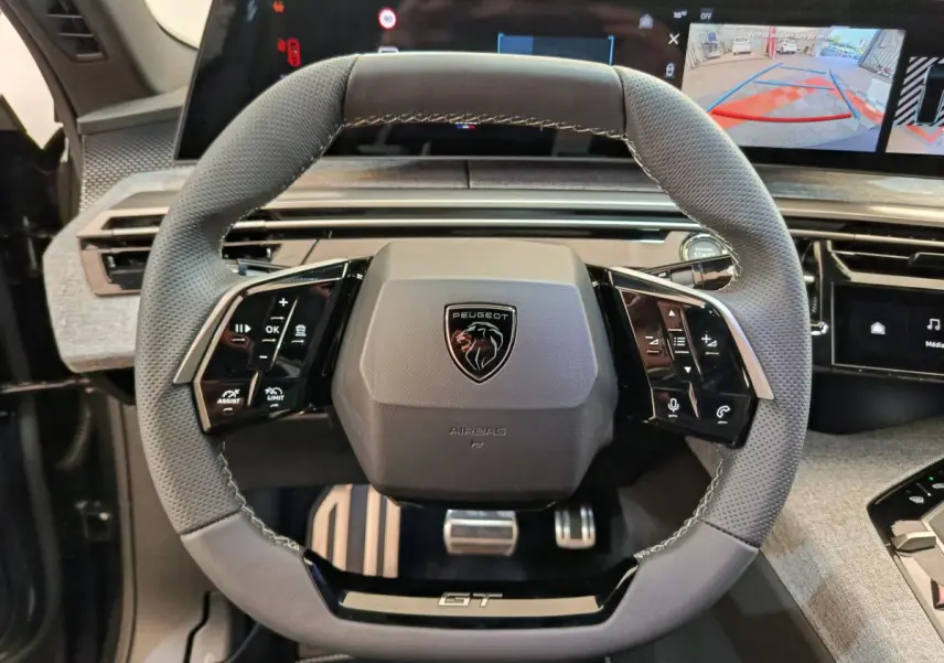 Vue rapprochée du volant cuir gris perforé Peugeot 3008 GT avec commandes intégrées et écran tactile de bord.