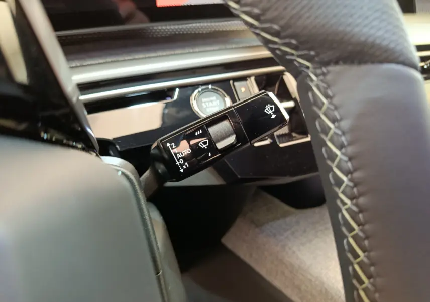 Gros plan sur la commande d’essuie-glace noire et le bouton start/stop dans l’habitacle du Peugeot 3008 noir 2025.
