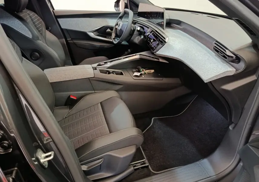 Vue intérieure côté conducteur du Peugeot 3008 1.2 Hybrid 145 GT 2025, avec tableau de bord moderne et sellerie noire.