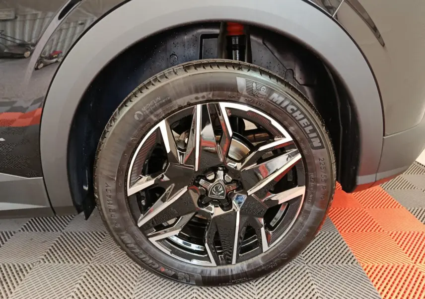 Gros plan sur la roue avant droite noire d’un Peugeot 3008 1.2 Hybrid 145 GT avec jante alliage au design moderne.
