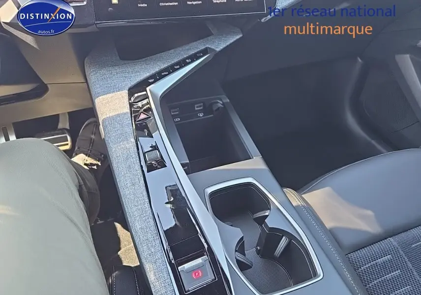 Vue rapprochée de la console centrale grise et noire du Peugeot 5008 Hybrid 145 GT avec porte-gobelets et commandes tactiles.
