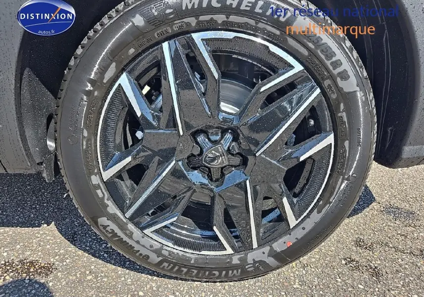 Gros plan sur la jante alu noire et argentée d'un Peugeot 5008 gris titane, pneu Michelin visible.