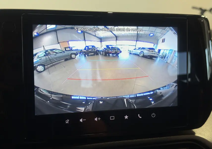 Vue arrière en caméra de recul de la Suzuki Swift 2025 noire, avec lignes de guidage et intérieur de garage visible.