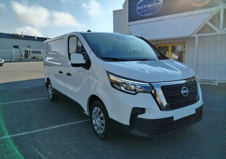 Vue 3/4 avant d'un utilitaire Nissan Primastar blanc 2025 avec calandre noire et pare-chocs noir mat, stationné en extérieur.
