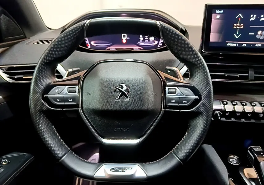 Vue rapprochée du volant cuir noir du Peugeot 3008 GT 2023 avec tableau de bord numérique et écran tactile central.
