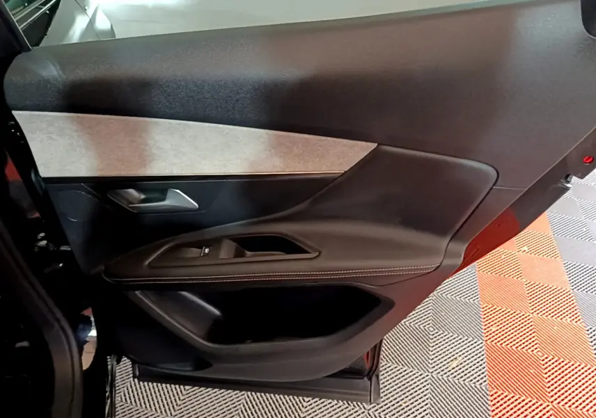 Vue intérieure côté gauche de la porte avant noire du Peugeot 3008 2023 avec garniture tissu et commandes électriques.