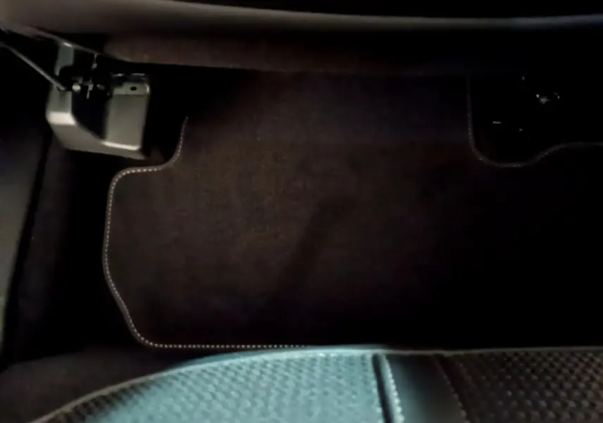 Vue intérieure du tapis de sol côté passager avant du Peugeot 3008 noir 2023, avec surpiqûres claires visibles.