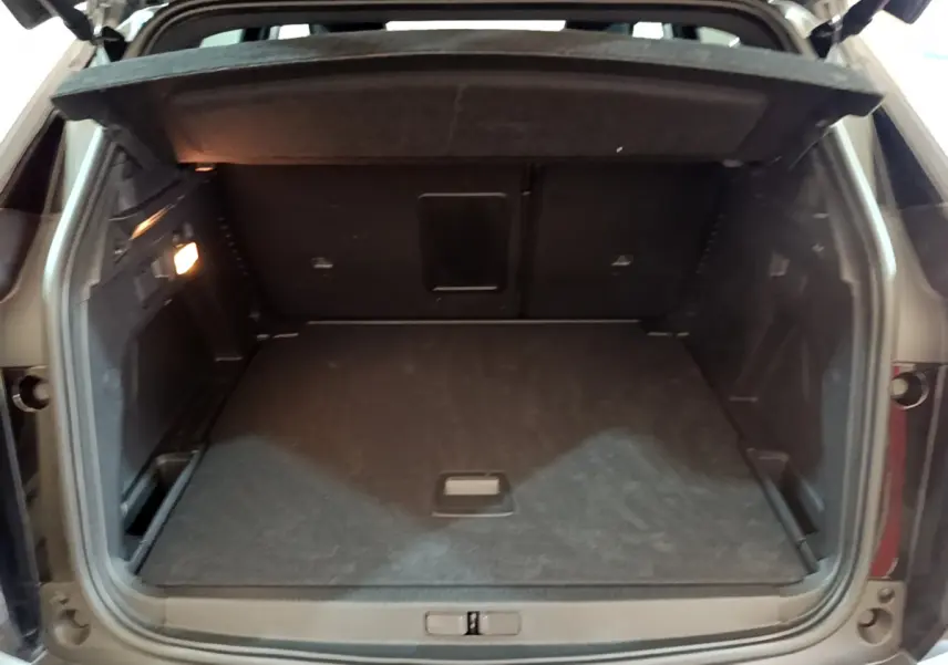 Coffre ouvert vu de l'arrière du Peugeot 3008 noir, montrant un espace de chargement spacieux et un éclairage intérieur.