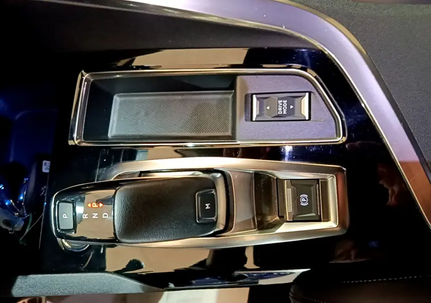 Vue rapprochée de la console centrale noire du Peugeot 3008 2023 avec levier de boîte auto et bouton Drive Mode.