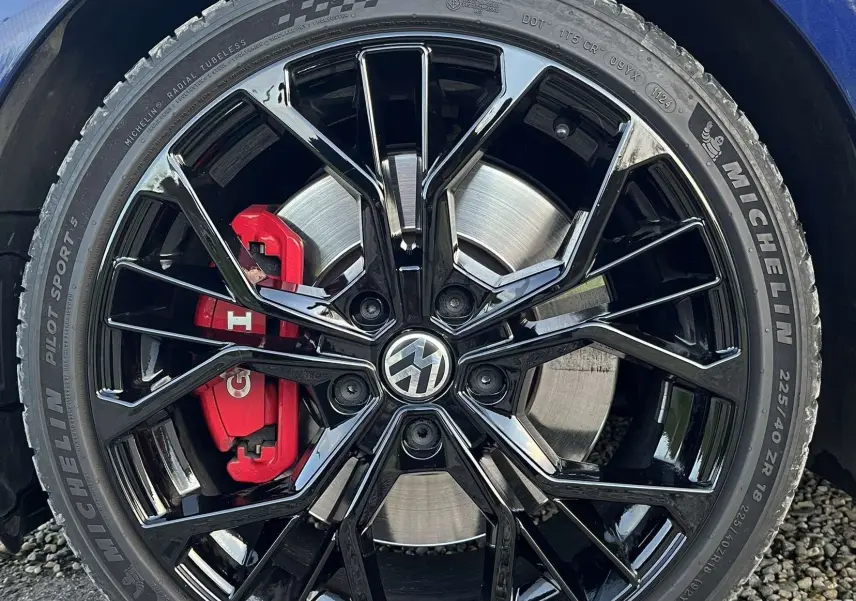Gros plan sur la roue avant gauche d'une Volkswagen Golf GTI Performance bleu lapiz, jante noire brillante et étrier rouge.