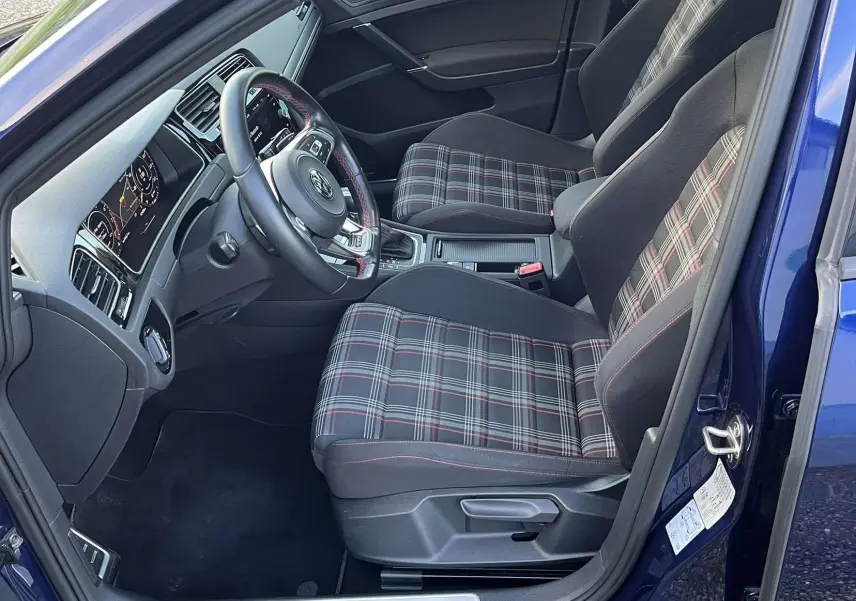 Intérieur côté conducteur d'une Volkswagen Golf VII GTI Performance bleu lapiz, sièges à motif tartan et volant cuir.