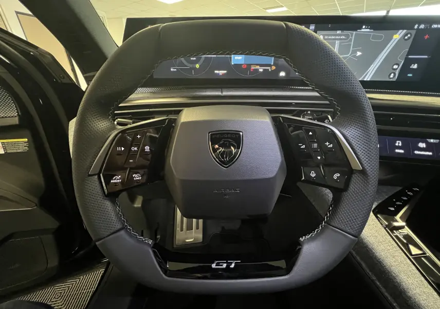 Vue rapprochée du volant cuir noir du Peugeot 5008 GT 2025 avec tableau de bord numérique et écran panoramique.