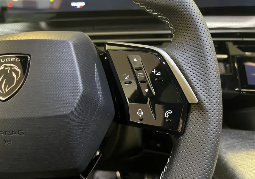 Gros plan sur la partie droite du volant perforé noir du Peugeot 5008 2025 avec commandes audio et téléphone intégrées.
