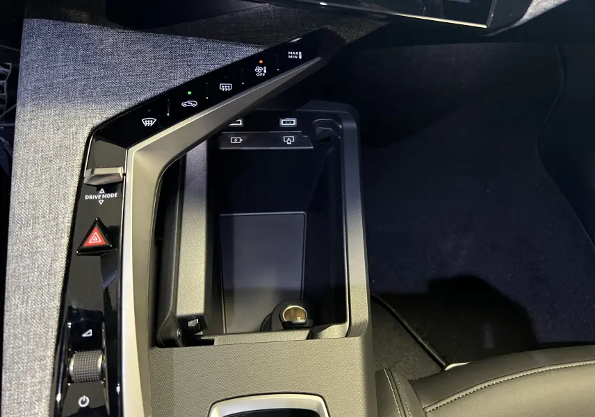 Gros plan sur la console centrale noire du Peugeot 5008 NV Hybrid 136 E-DCS6 GT avec commandes tactiles et rangement ouvert.