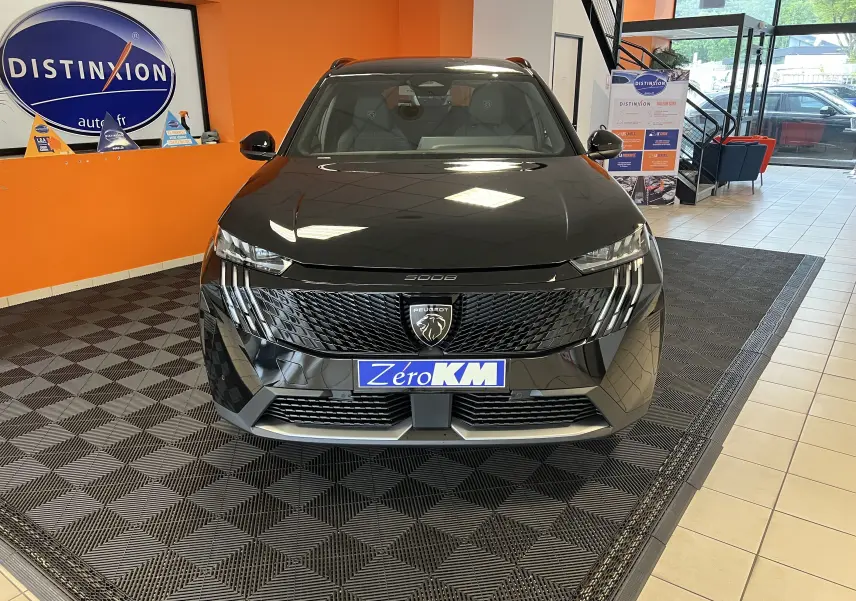 Vue frontale d'un Peugeot 5008 noir 2025 en showroom, mettant en valeur sa calandre moderne et ses phares LED distinctifs.