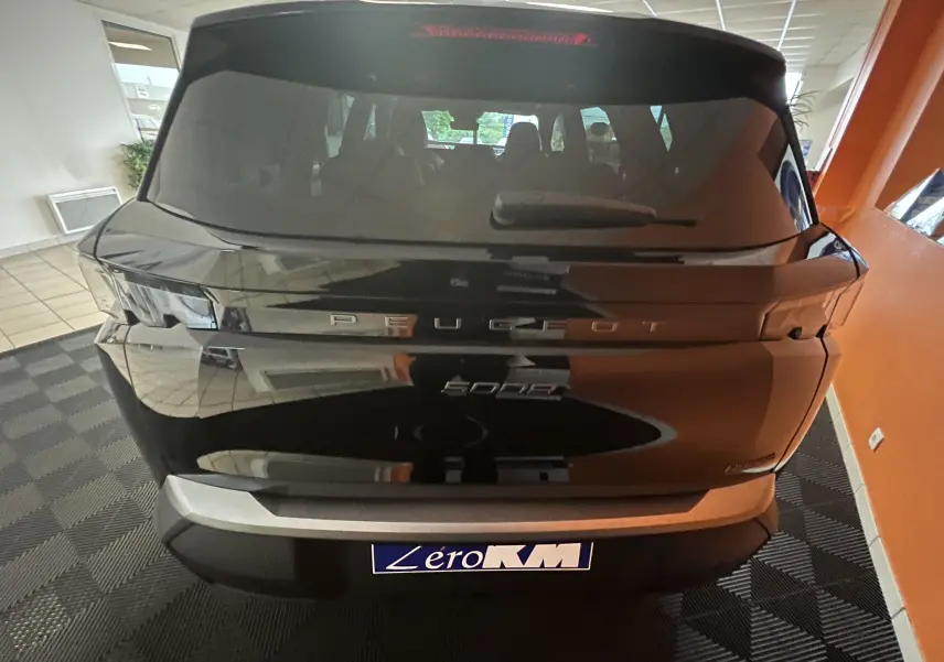 Vue arrière d'un Peugeot 5008 noir 2025 avec hayon motorisé et feux arrière modernes dans un showroom.