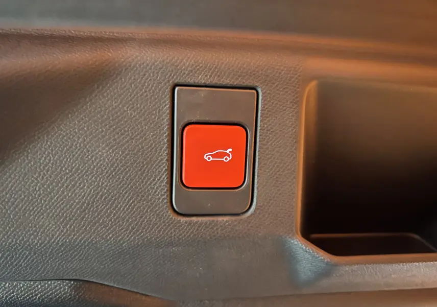 Bouton rouge d'ouverture du hayon motorisé sur la garniture intérieure d'une Peugeot 5008 NV Hybrid 136 E-DCS6 GT noire.