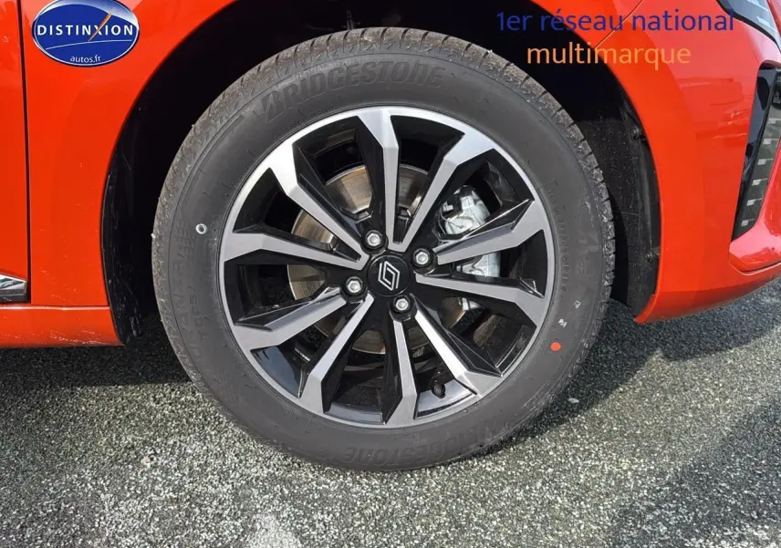 Gros plan sur la jante alu noire et grise du côté avant droit d'une Renault Clio V orange Valencia.