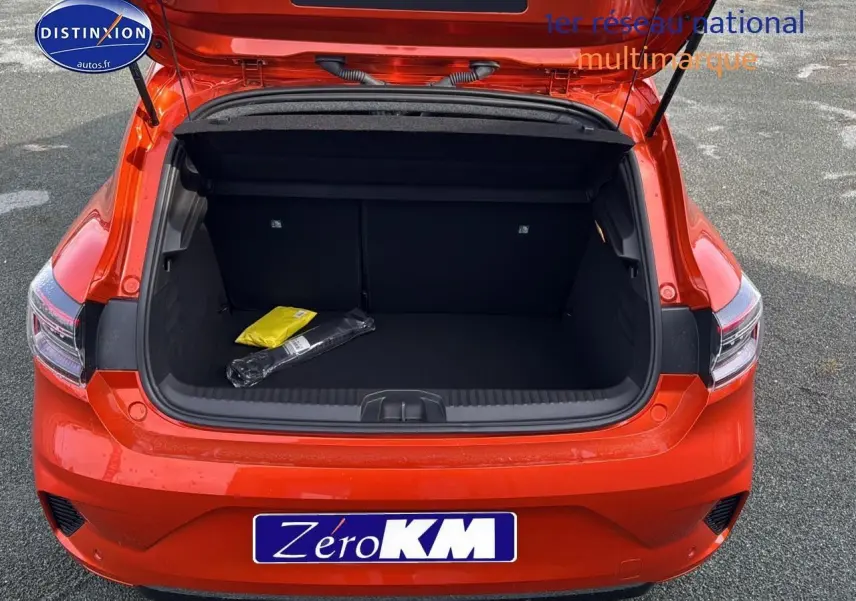 Coffre ouvert vu de l'arrière d'une Renault Clio V 1.6 e-tech 145 techno orange Valencia sur parking.