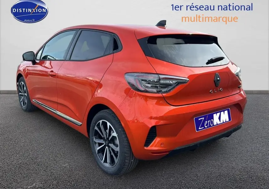 Vue 3/4 arrière droite d'une Renault Clio V orange Valencia avec jantes alliage et becquet arrière.