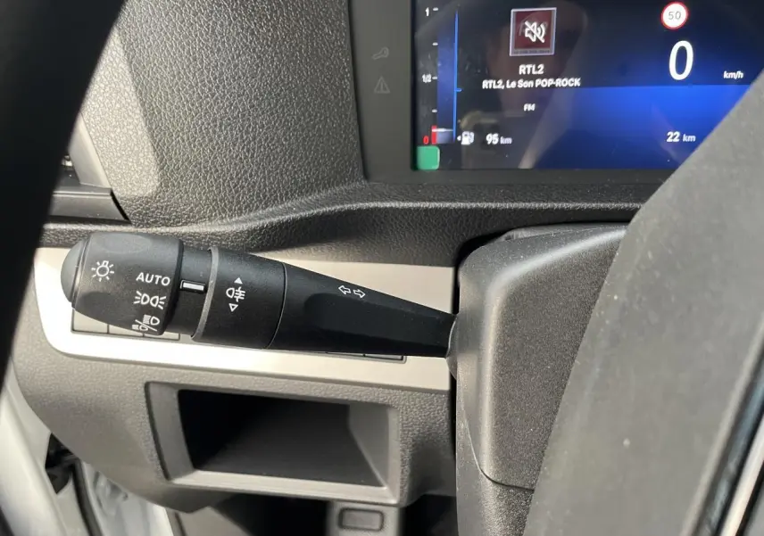 Gros plan sur la manette des feux et clignotants à gauche du volant dans l'habitacle d'un Opel Vivaro blanc 2024.