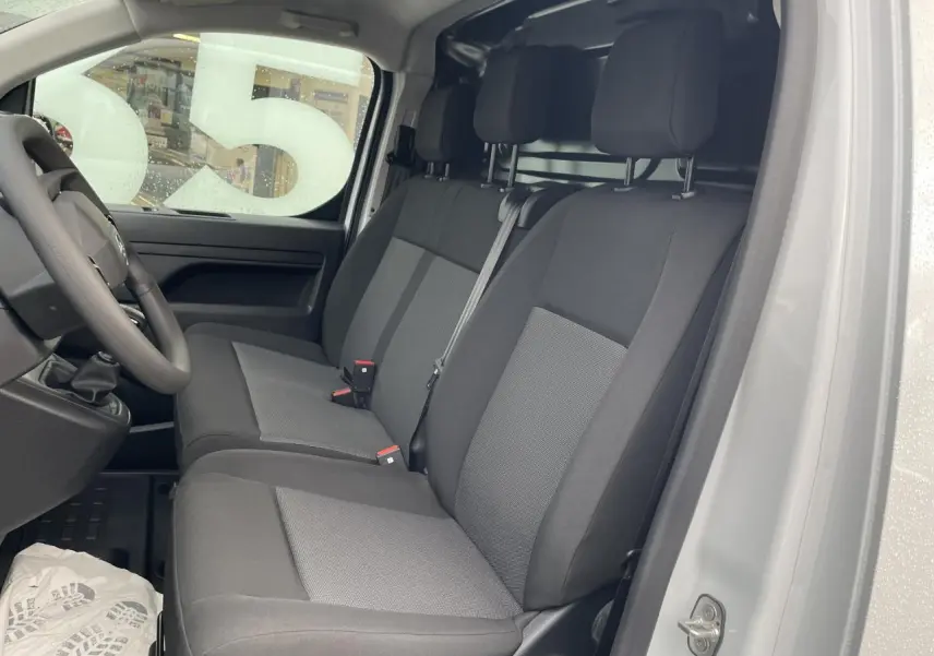 Intérieur côté conducteur d'un Opel Vivaro blanc 2024, montrant la banquette 3 places en tissu bi-ton noir et gris.