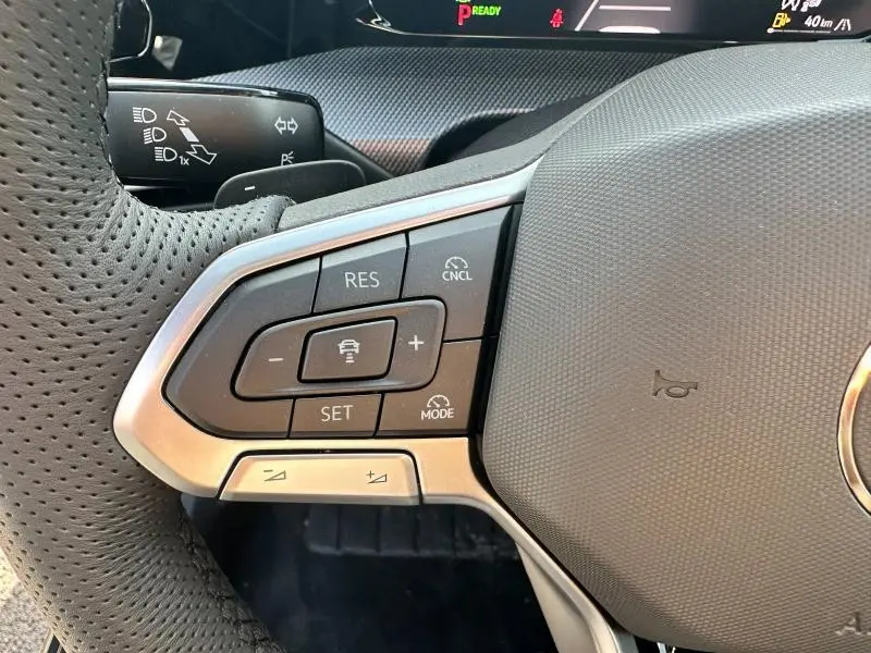 Gros plan sur le volant côté gauche de la Volkswagen Golf gris 2025, avec commandes de régulateur de vitesse intégrées.