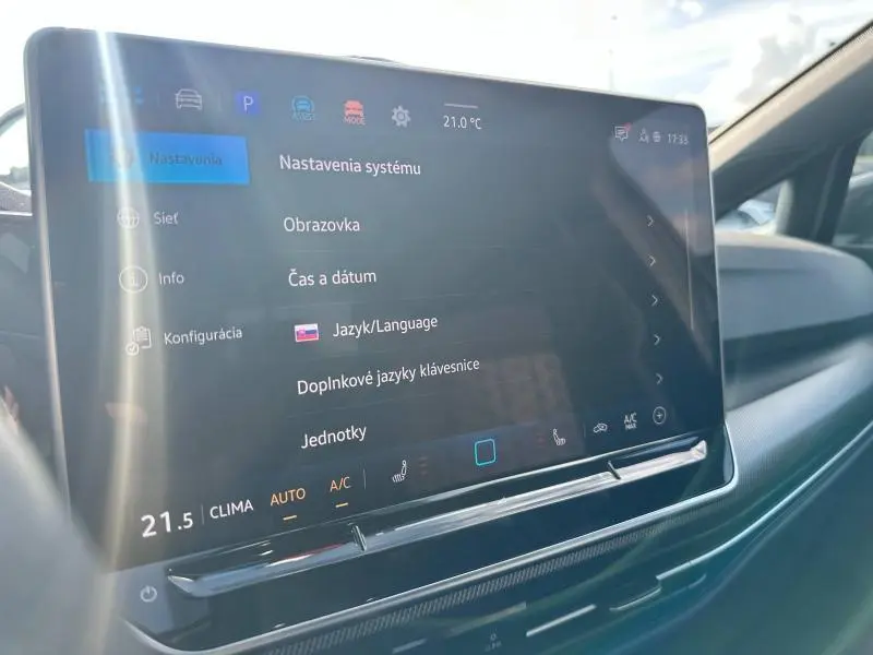 Écran tactile central du tableau de bord de la Volkswagen Golf 2025, affichant les réglages système en intérieur lumineux.