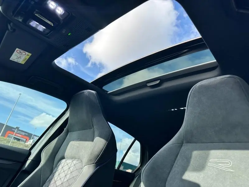 Vue intérieure de la Volkswagen Golf 1.5 eTSI R-Line 2025 avec toit ouvrant panoramique et sièges sport gris.