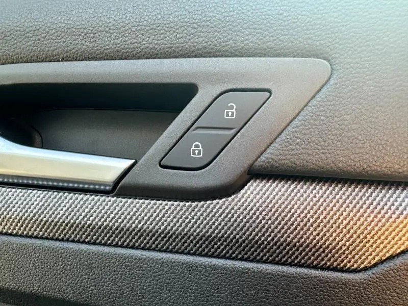 Gros plan sur la poignée intérieure et les boutons de verrouillage de la porte côté conducteur d'une Volkswagen Golf gris 2025 R-Line.