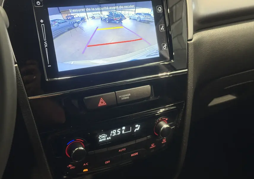 Vue rapprochée de l'écran multimédia affichant la caméra de recul d'un Suzuki Vitara beige 2023 en intérieur showroom.