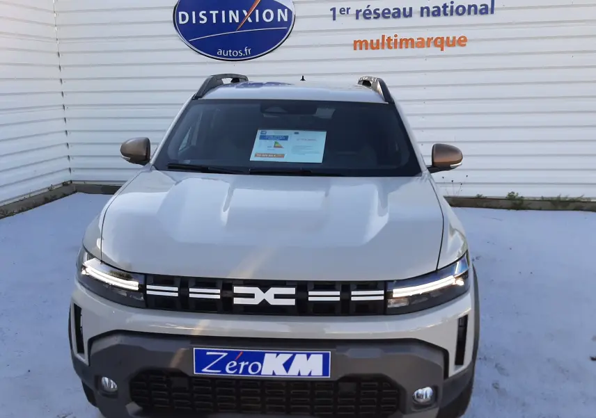 Vue avant d'un Dacia Duster 1.6 Hybrid 140ch Extreme couleur Sandstone avec calandre noire et phares LED allumés.