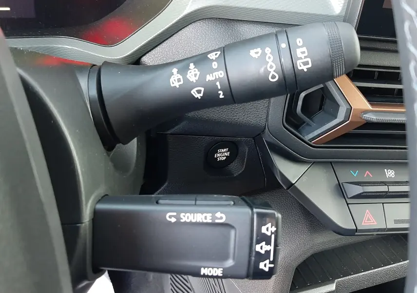 Détail du commodo gauche et bouton start du tableau de bord du Dacia Duster 1.6 Hybrid 2025, intérieur gris.