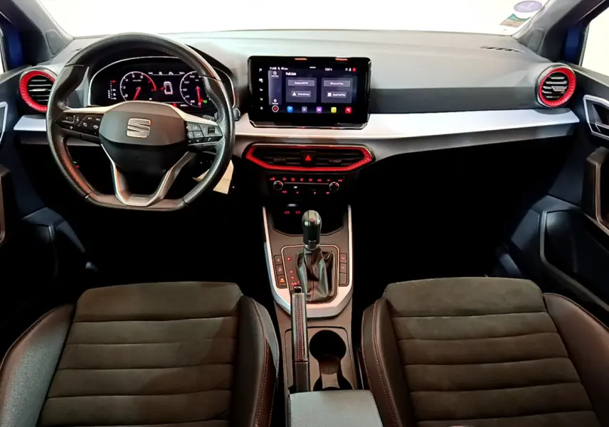 Intérieur du SEAT Arona bleu 2022, vue de face sur le tableau de bord avec écran tactile et détails rouges autour des aérateurs.
