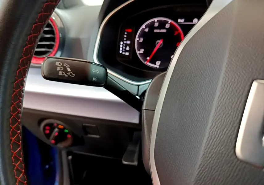 Gros plan sur le volant cuir noir avec surpiqûres rouges et tableau de bord numérique du SEAT Arona bleu 2022.