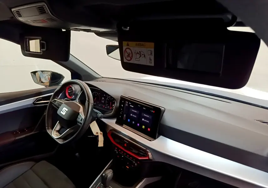 Intérieur du SEAT Arona 2022 côté conducteur, tableau de bord moderne avec écran tactile et accents rouges.
