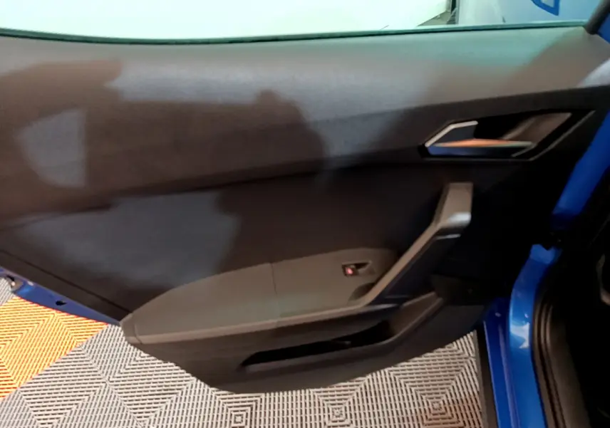 Vue rapprochée de la porte côté droit bleu du SEAT ARONA 2022, avec poignée intérieure et panneau noir.