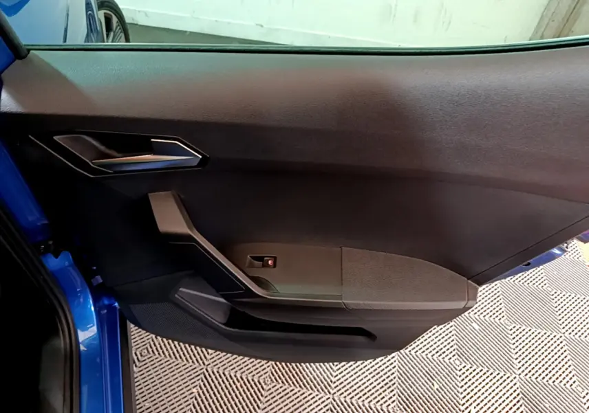 Vue rapprochée de la porte côté gauche bleu du SEAT ARONA 2022, avec poignée et garniture intérieure noire.