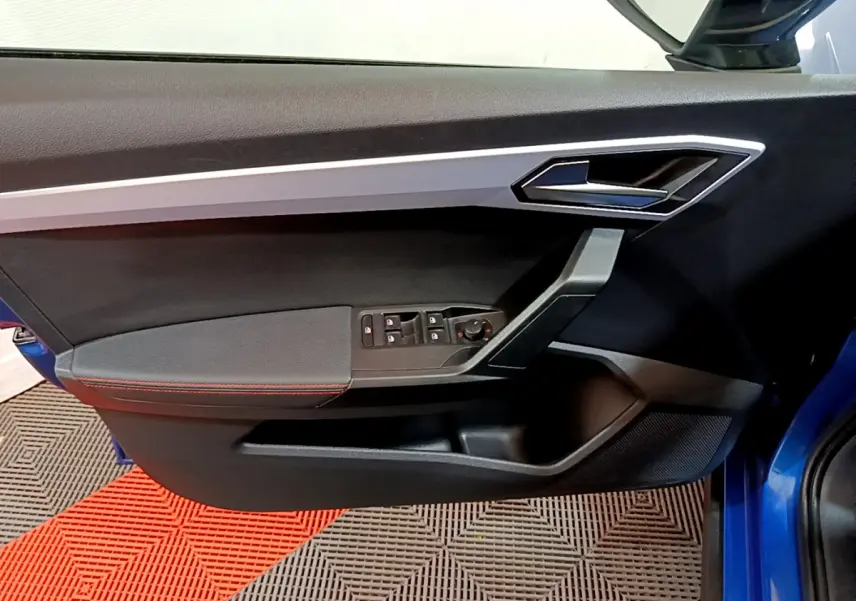 Vue rapprochée de la porte avant gauche bleu du SEAT Arona 2022 avec commandes électriques et poignée argentée.