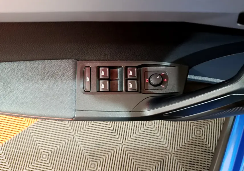 Vue rapprochée des commandes de lève-vitres et rétroviseurs sur la portière côté conducteur d'une SEAT Arona bleu 2022.