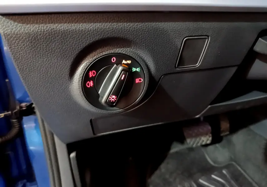 Gros plan sur le sélecteur d'éclairage noir du tableau de bord côté gauche dans une SEAT Arona bleu 2022.