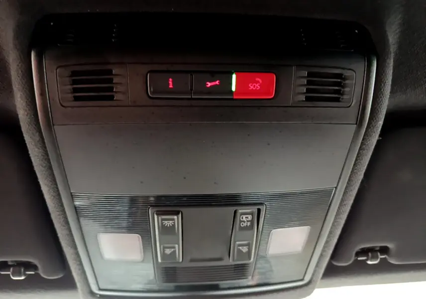 Vue en plongée du panneau de commandes de toit intérieur du SEAT Arona bleu, avec bouton SOS rouge allumé.