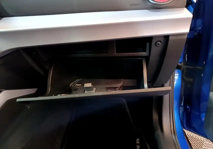 Vue rapprochée de la boîte à gants ouverte côté passager d'une SEAT Arona bleu 2022 avec tableau de bord gris clair.