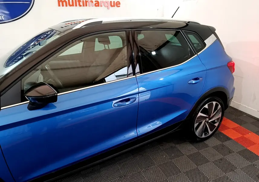 Vue de profil côté gauche du SEAT Arona bleu 2022 avec toit noir et jantes alliage distinctives.