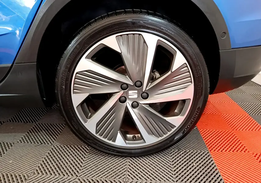 Gros plan sur la roue avant droite d'un SEAT Arona bleu 2022 avec jante alliage au design moderne.