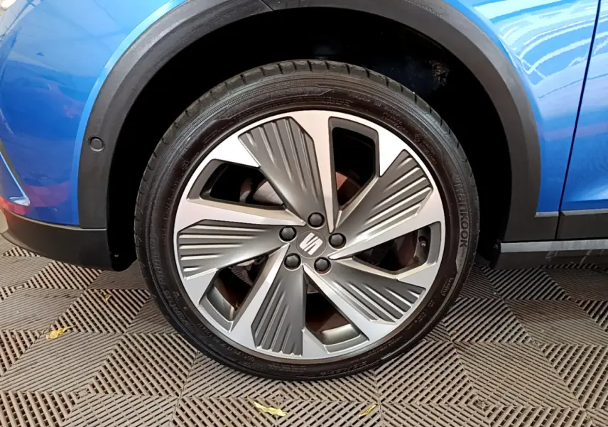 Gros plan sur la roue avant droite du SEAT Arona bleu 2022, mettant en valeur la jante alu au design moderne.