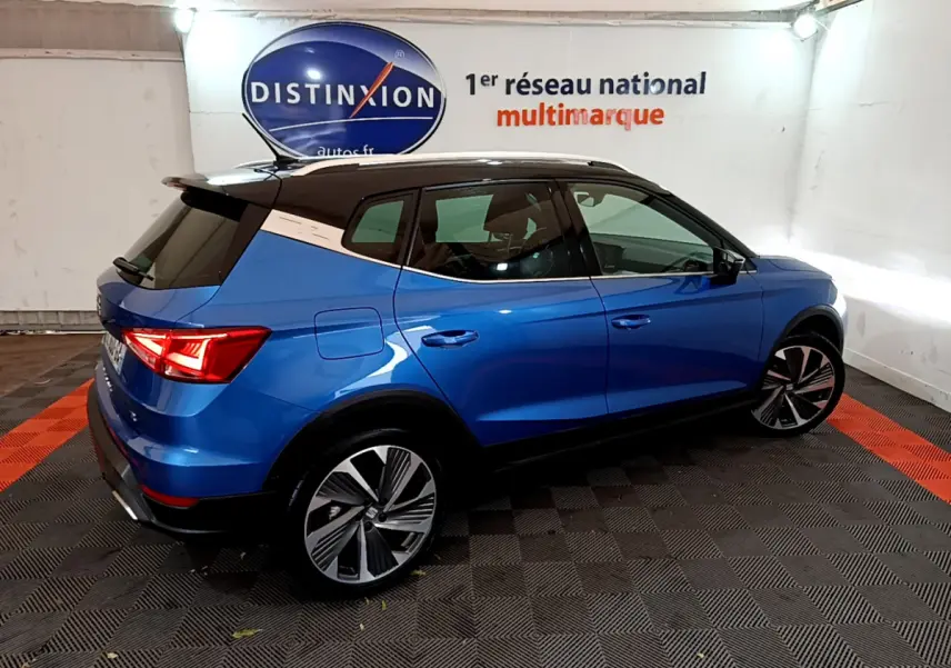 SEAT Arona bleu 2022 en vue 3/4 arrière droit, toit noir et jantes alliage distinctives dans showroom