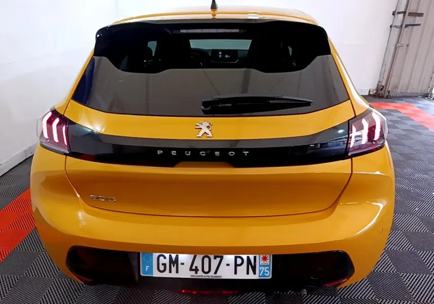 Vue arrière d'une Peugeot 208 jaune 2023 avec feux LED distinctifs et lunette arrière teintée.