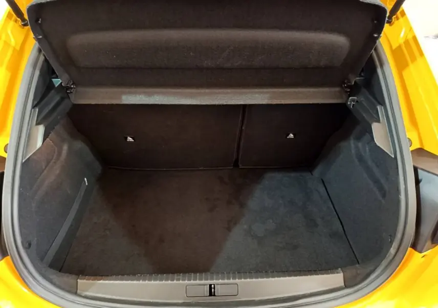 Coffre ouvert vu de dessus d'une Peugeot 208 jaune 2023, montrant un espace de rangement propre et spacieux.
